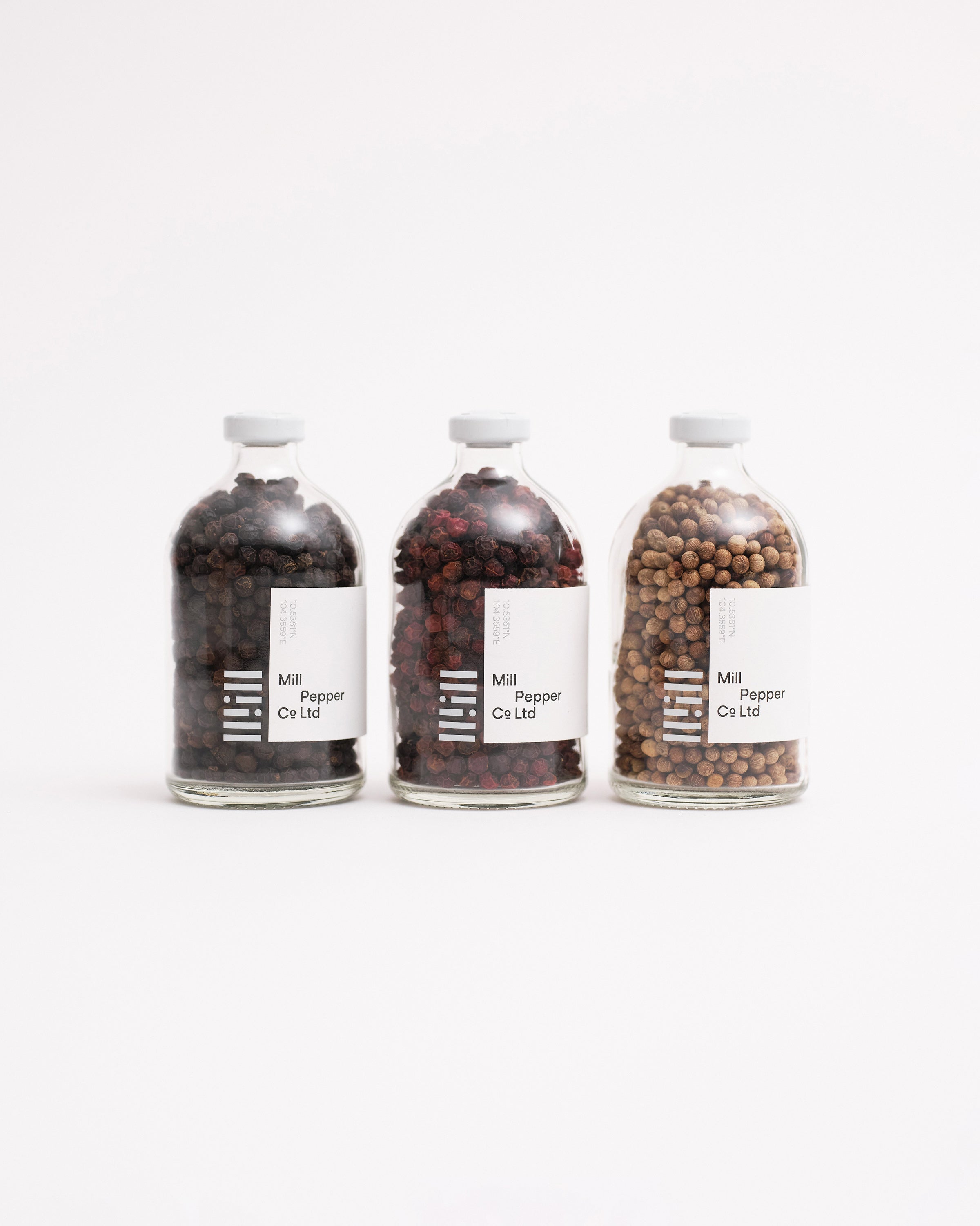 Black, red and white Kampot peppercorns shot on white background.