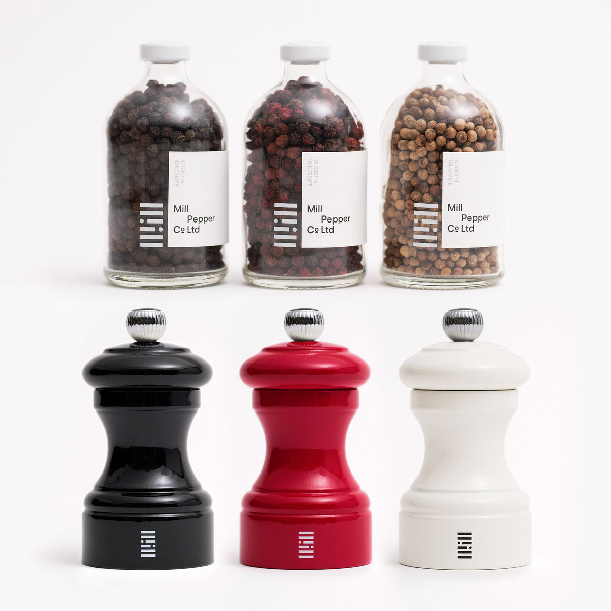 Black, red and white whole pepper jars and red, white, black pepper mills shot on white. 