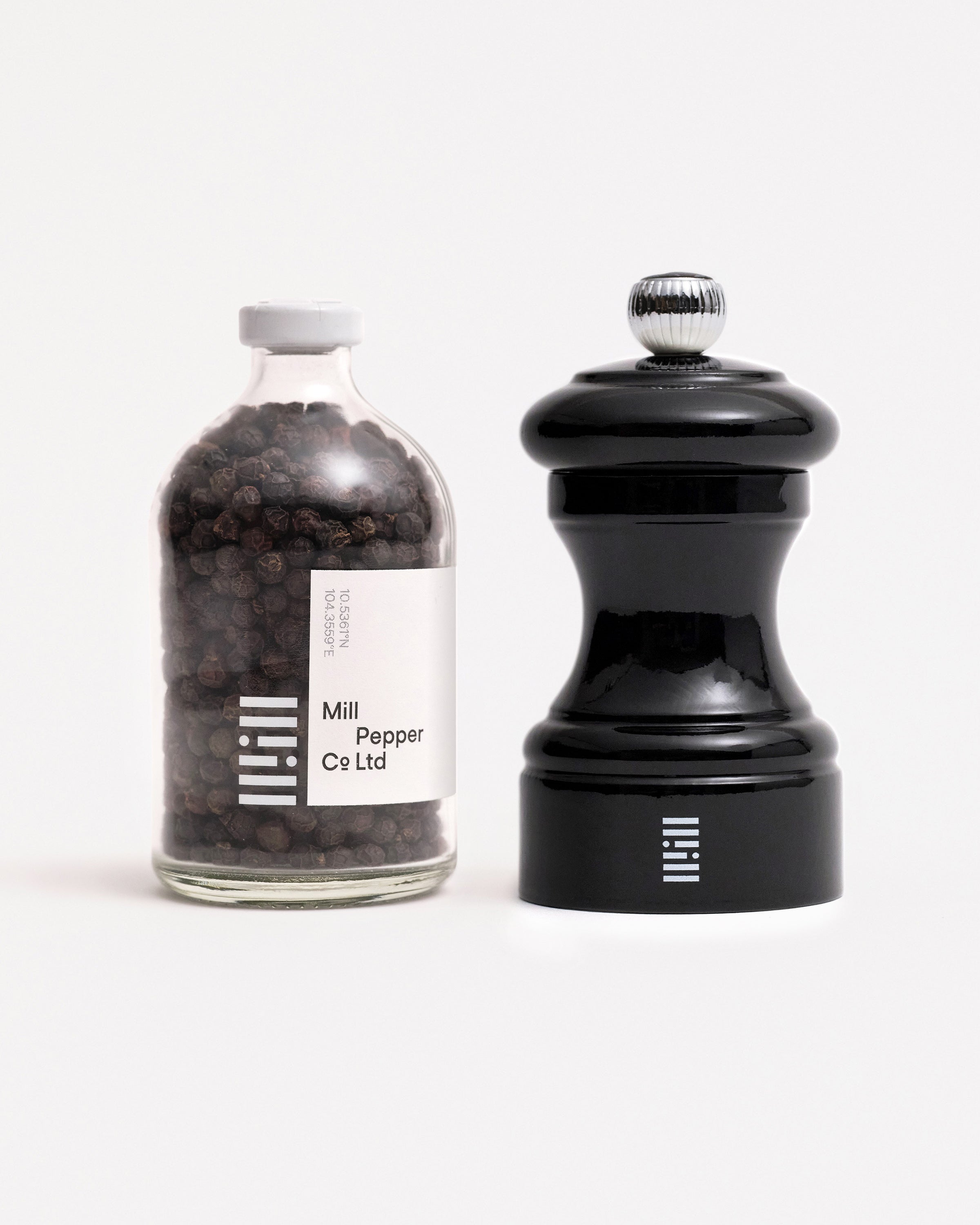 Black pepper and black Peugeot Mill shot on white.